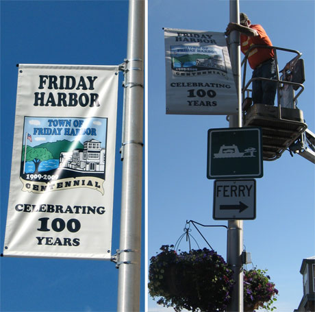 The Chamber's Debbie Pigman reports: "Town crew members, Jeff Peacock and Dave Smith (not shown) are caught in the act of putting up our Town of Friday Harbor Centennial Bannners.  The flying of the banners coincides with the final quarter of celebration of the town's first 100 years!"