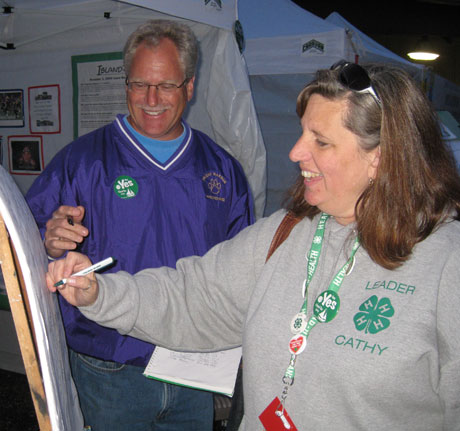 Eric Jangard signs up Cathy Cole as a levy supporter at the County Fair....