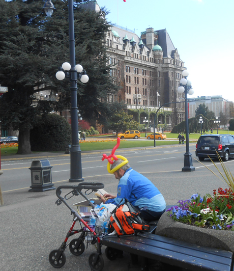 A street perfomer who makes balloon animals takes a quick iPhone break, on a sunny weekend day near the Empress Hotel on the Inner Harbour.